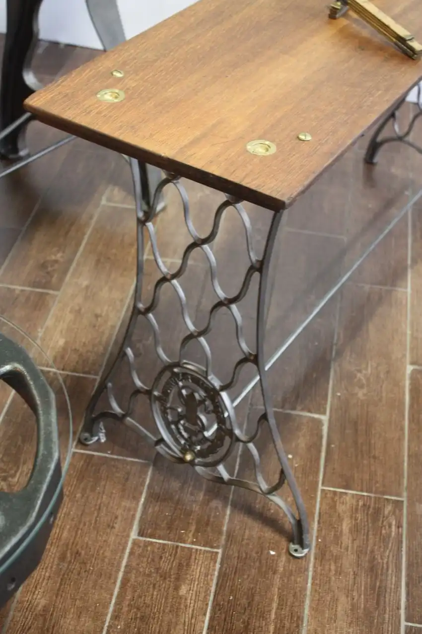 This table is made from the sets of a vintage sewing machine. The rich wood top is secured with interesting brass fittings.