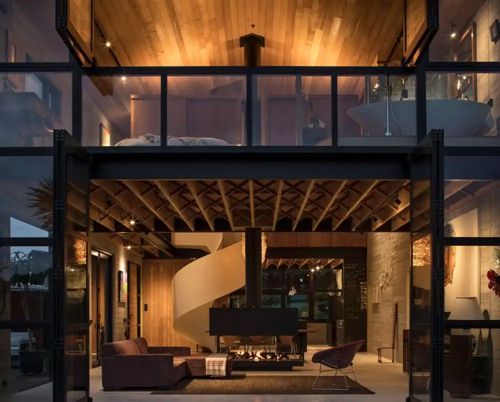 A fireplace hangs at the core of the house, being mounted to the rood, above the mezzanine floor