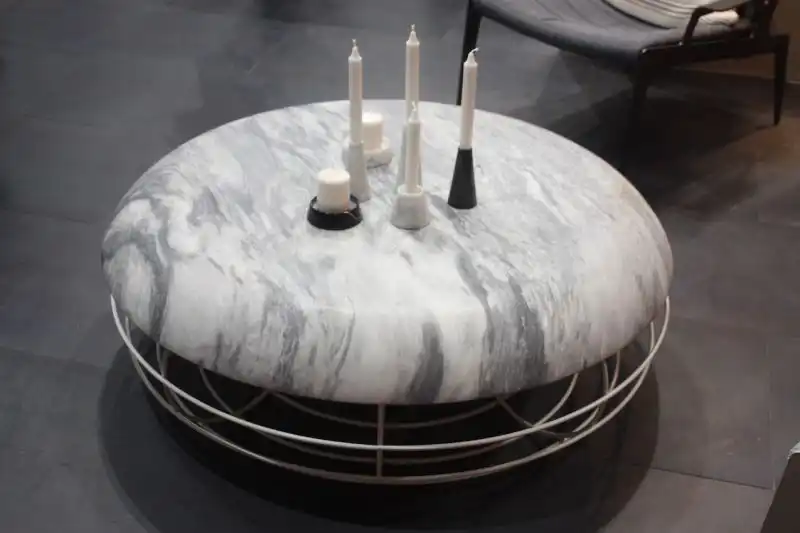 With the rounded shape of an ottoman, this marble topped coffee table by Atipico invites you to put your feet up as well. The rounded metal base adds to the impression that it's as much ottoman as table.