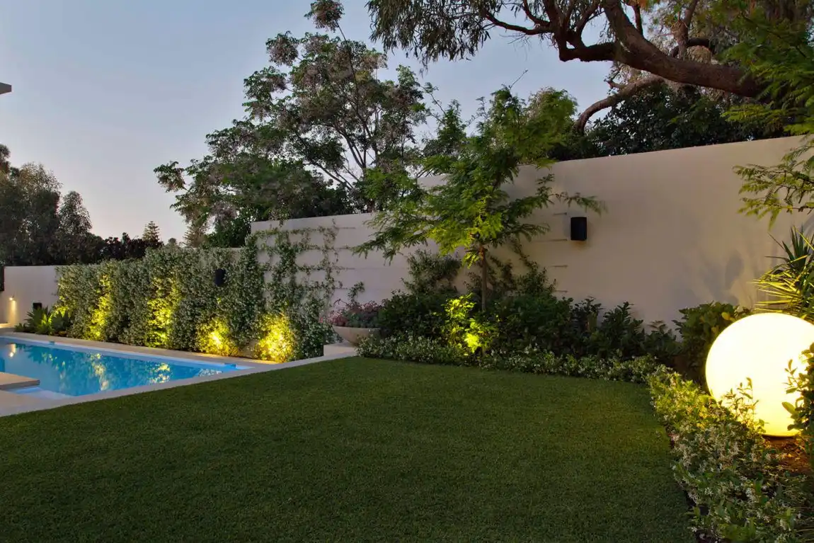 Backyard swimming pool and lush vegetation with lights