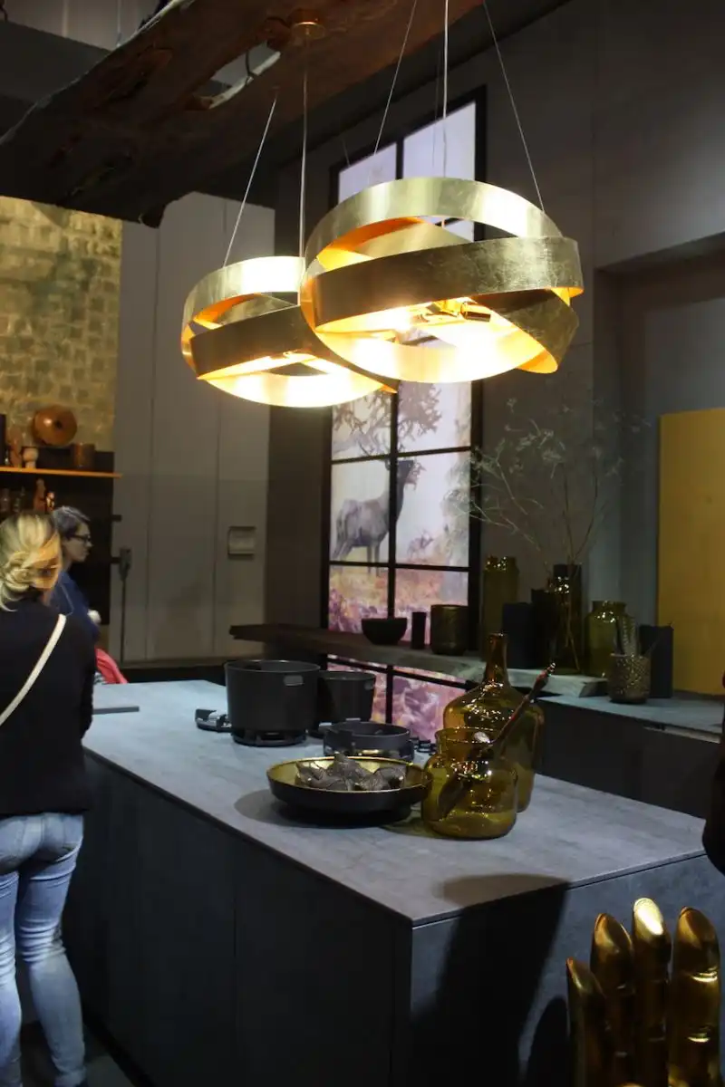 Alno used these island lighting fixtures made from circular bands of gold metal to lend a bit of shine to the neutral colored kitchen.