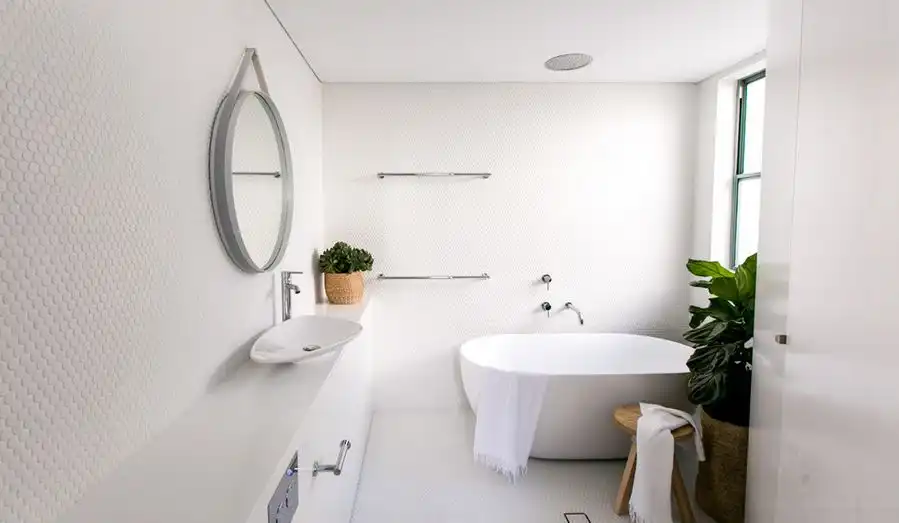 Contemporary white bathroom with penny tiles on wall and freestanding tub