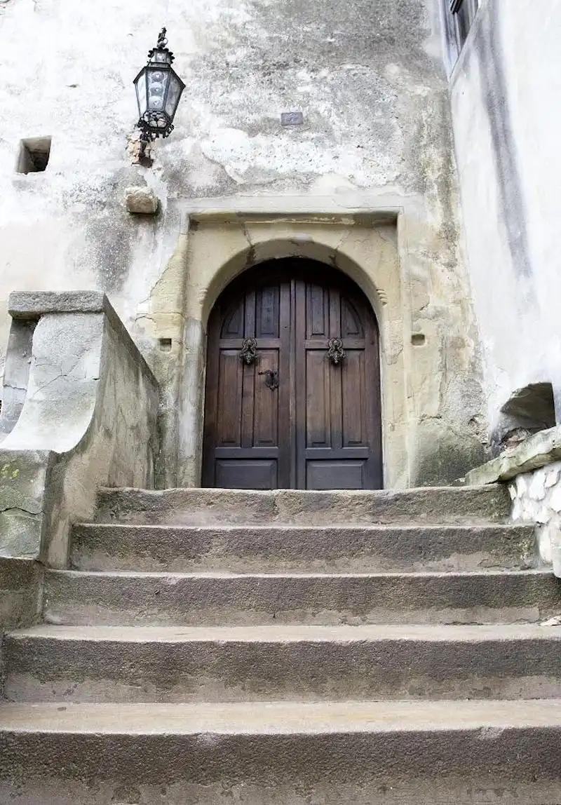 Visitors are welcomed inside the castle through a massive pair of wooden doors at the stop of a concrete staircase