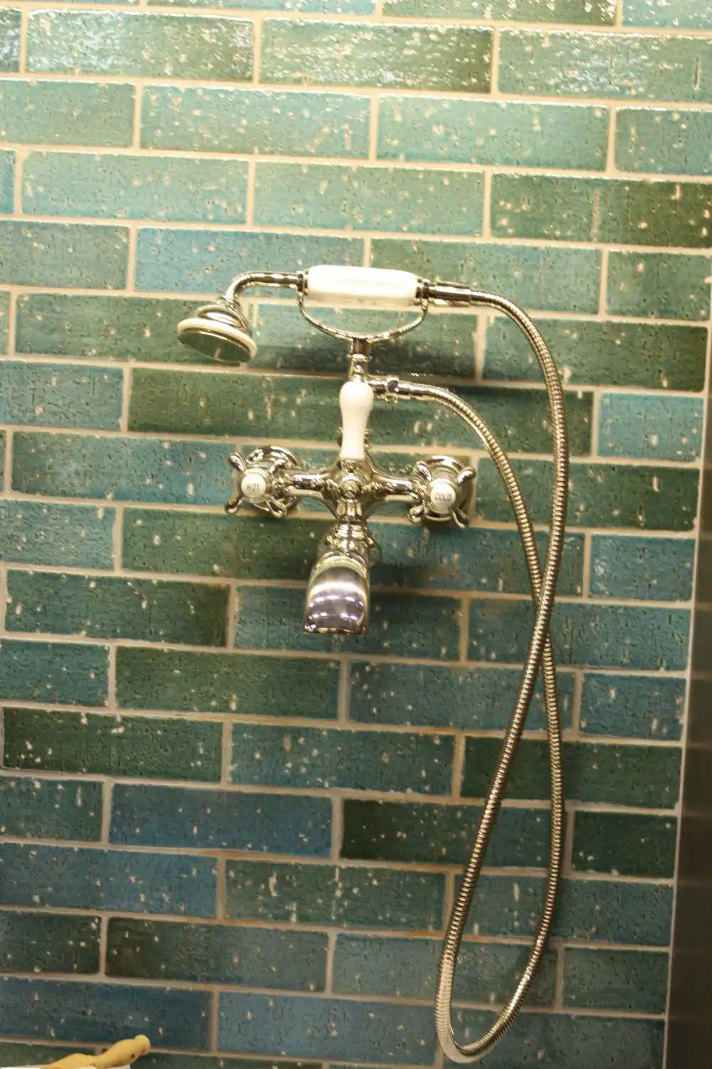 Green shower tiles and victorian faucet