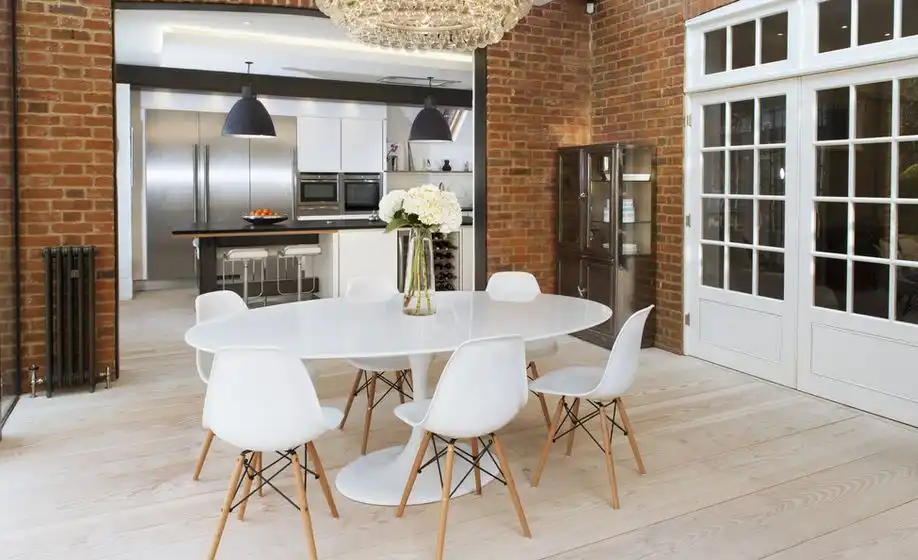 Industrial touch for dining area with exposed bricks on wall and tulip oval table