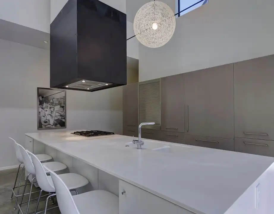 The sleek kitchen features a large hood and a round pendant light.