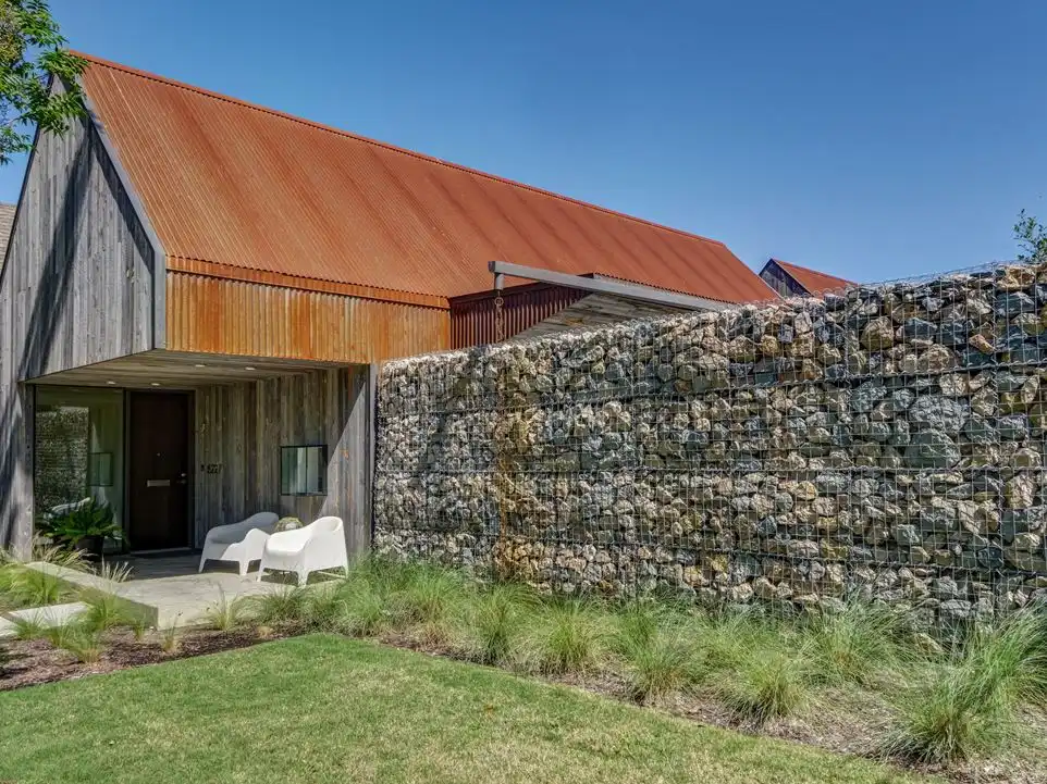 The gabion wall is an unexpected architectural element for a residential building.