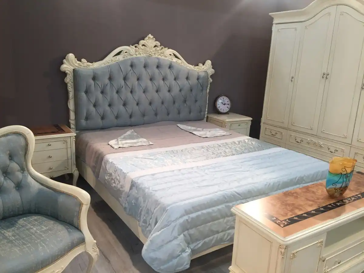 Luxury bedroom set in white with blue tufted headboard and armchairs