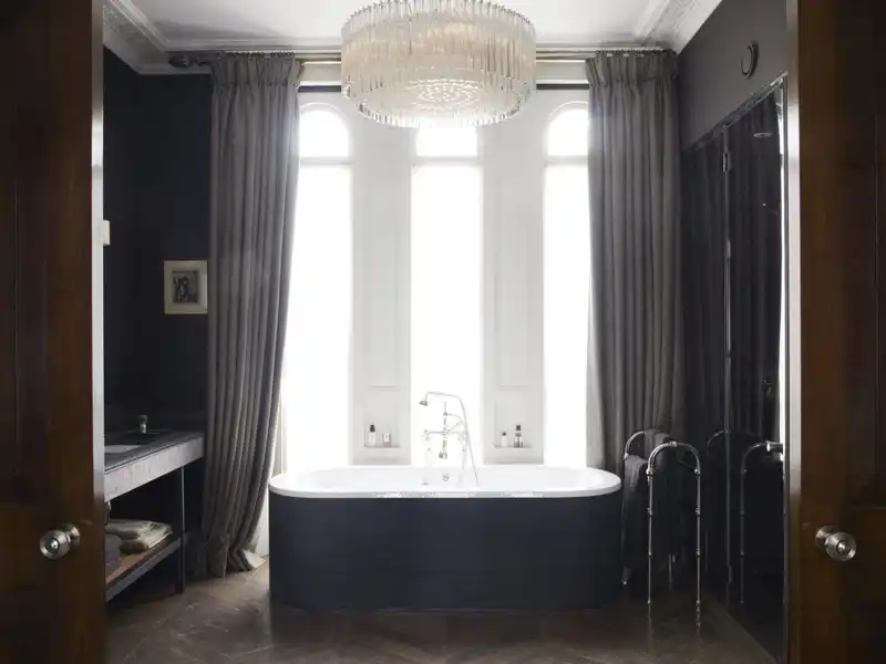 Masculine bathroom design with chandelier and large curtains