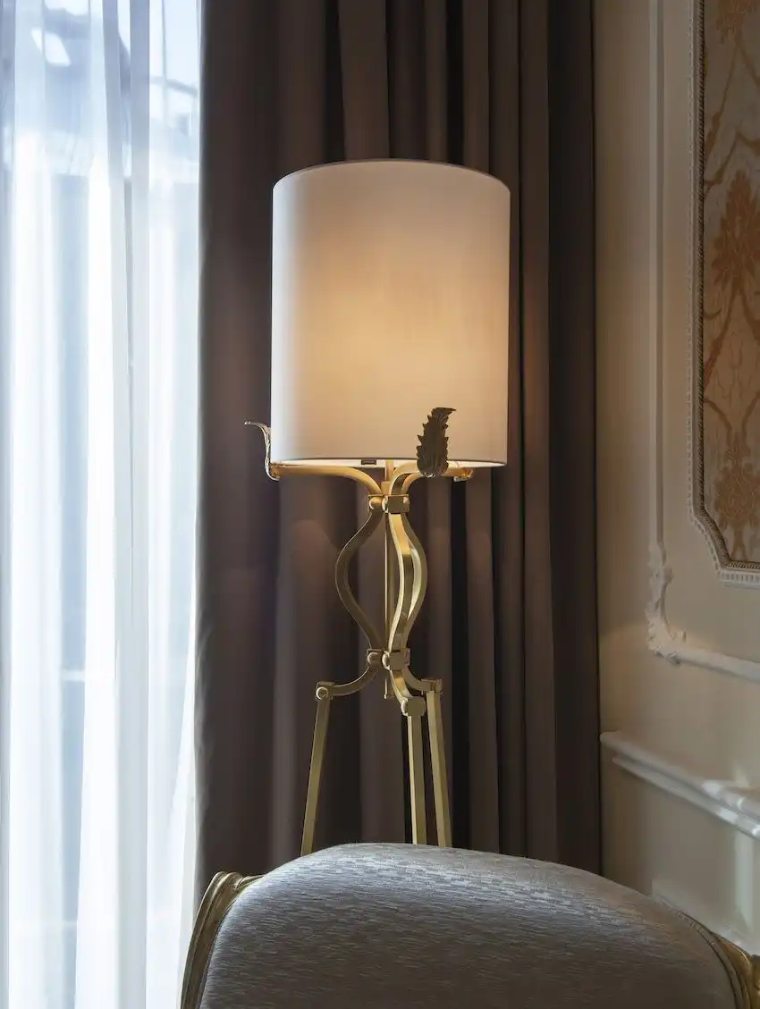A floor lamp has an elegant brass base with leaf details.