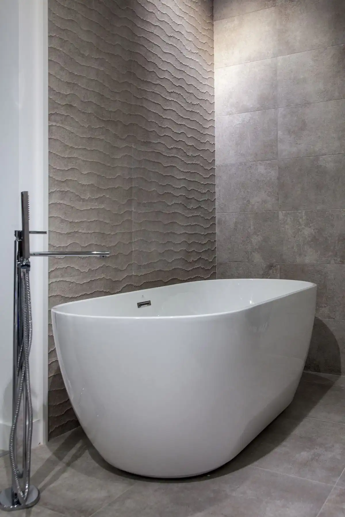 Minimalist soaking tub and waves wall tiles