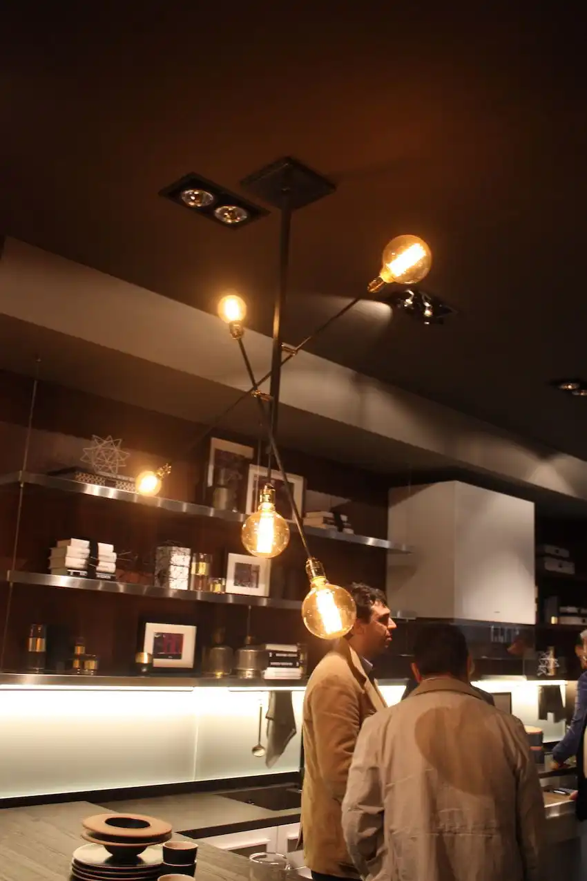Simple metal rods with bulbed ends come together in a modern and moody kitchen lighting fixture. The fixture is versatile and works well in Scavolini's contemporary setting.