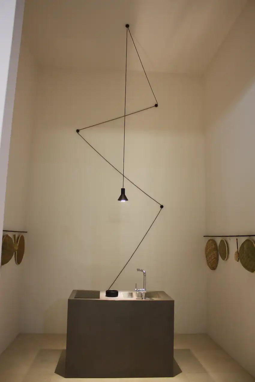 A small kitchen pendant lighting fixture becomes a dramatic design element in the hands of the Sanwa Company. Using the space to highlight the small kitchen island is a unique way to elevate the design.