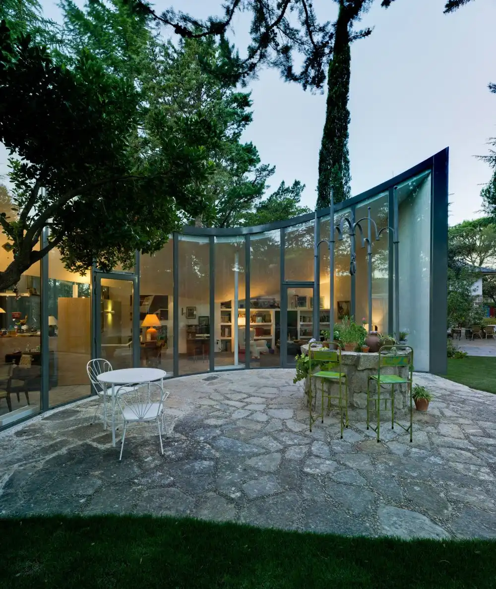 A small table and a few chic garden chairs are spread across the stone patio which surrounds the well