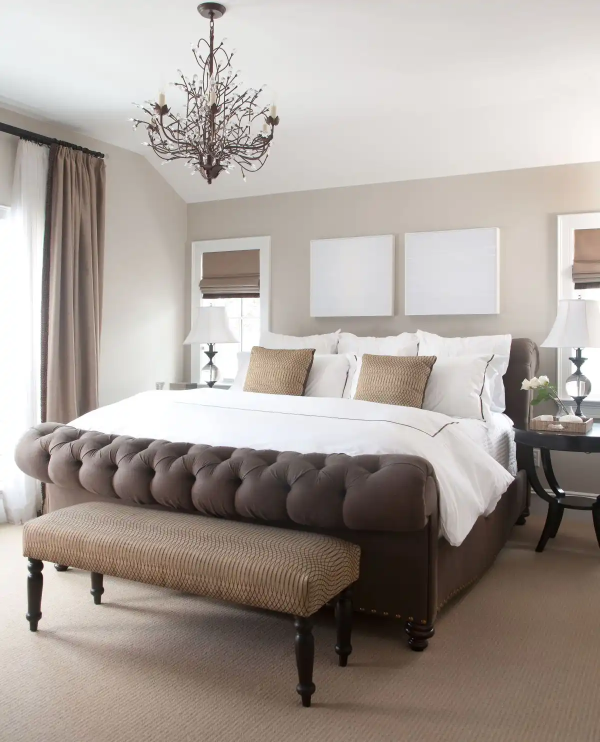 Tufted brown bed and chandelier over