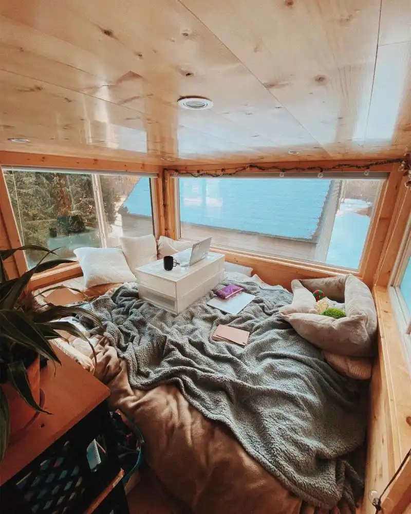 The bedroom is framed in by glass windows which make up for the low ceiling