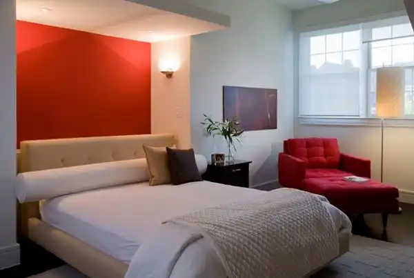 Red armchair compliment the wall above bed