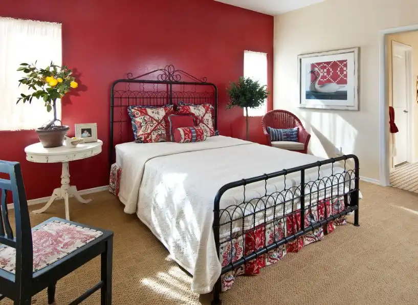 Red wall and black iron frame for bed