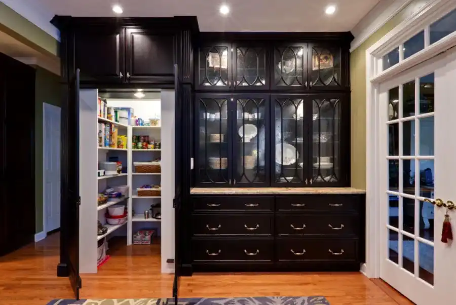 Traditional kitchen pantry idea in Atlanta with glass front cabinets and black cabinets
