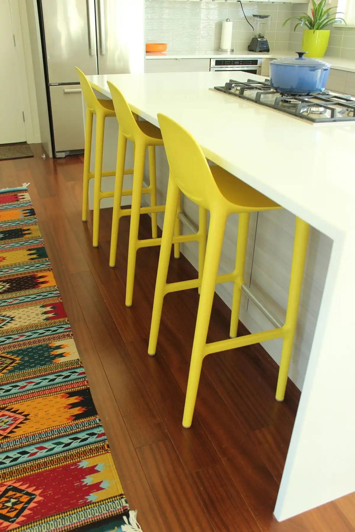white waterfall countertop with yellow bar chairs