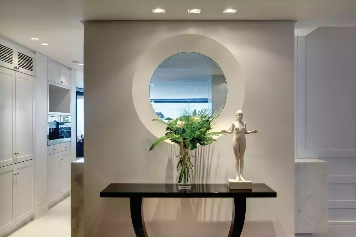 A stylish console table complemented by a small decorative statue and accent lighting adds a dramatic twist to the decor
