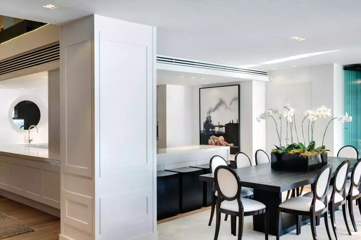 The dining area features a simple wood table framed by eight chic and timeless chairs with matching frames