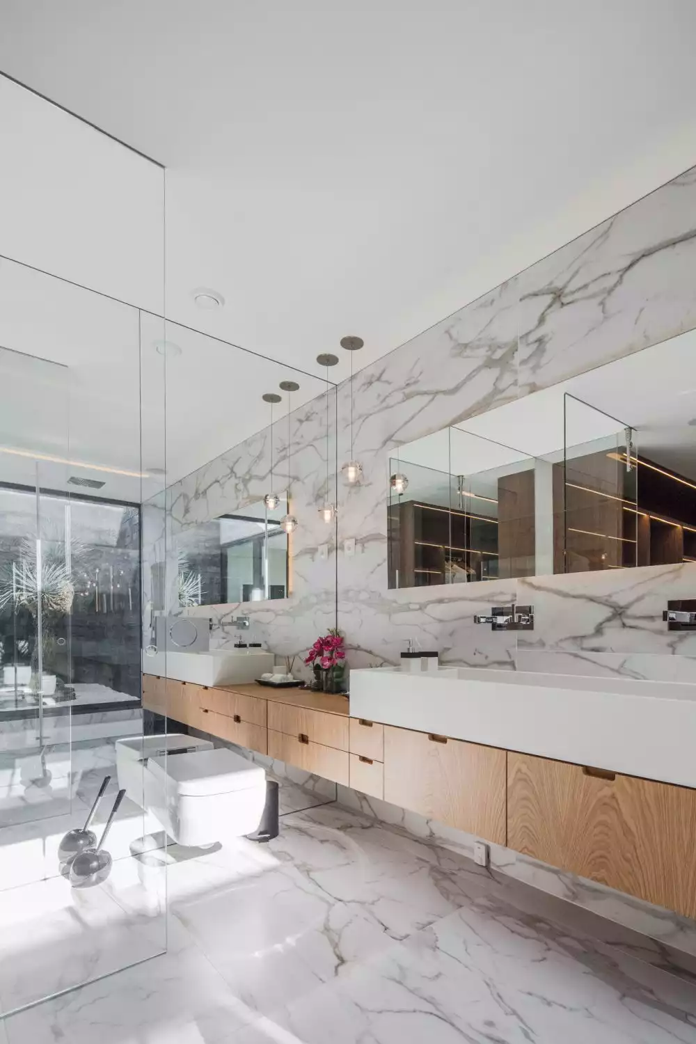 The master bathroom features an eclectic design with marble walls and flooring and large mirrors