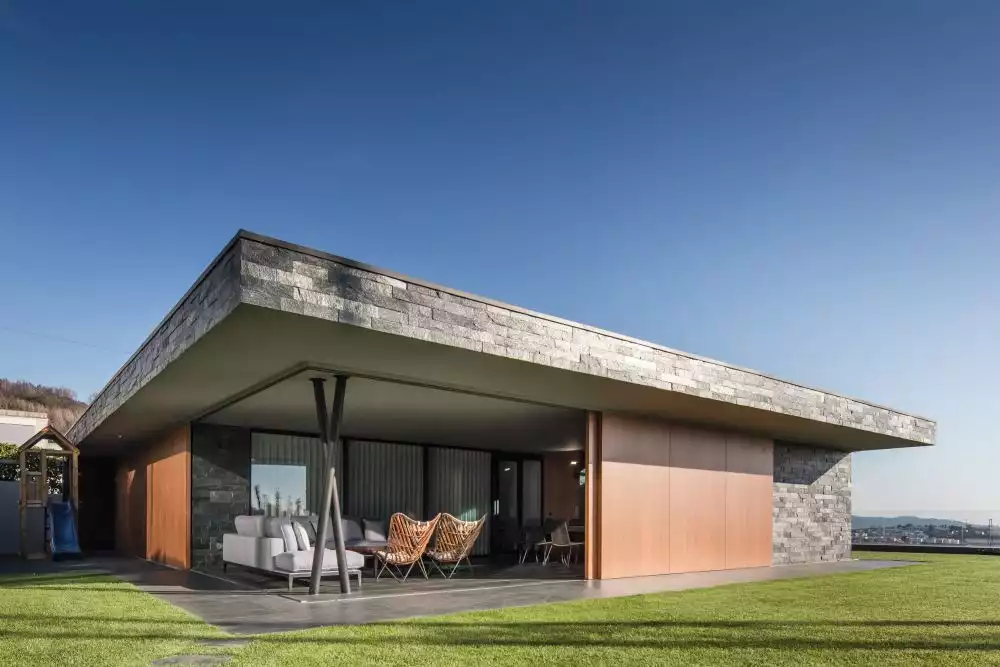 The ground floor living spaces feature large sliding doors and walls which expose them to the landscape and the views