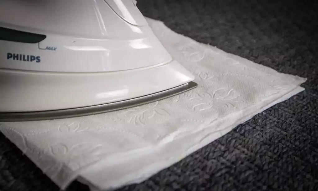 Melting wax in carpet with an iron and paper towels