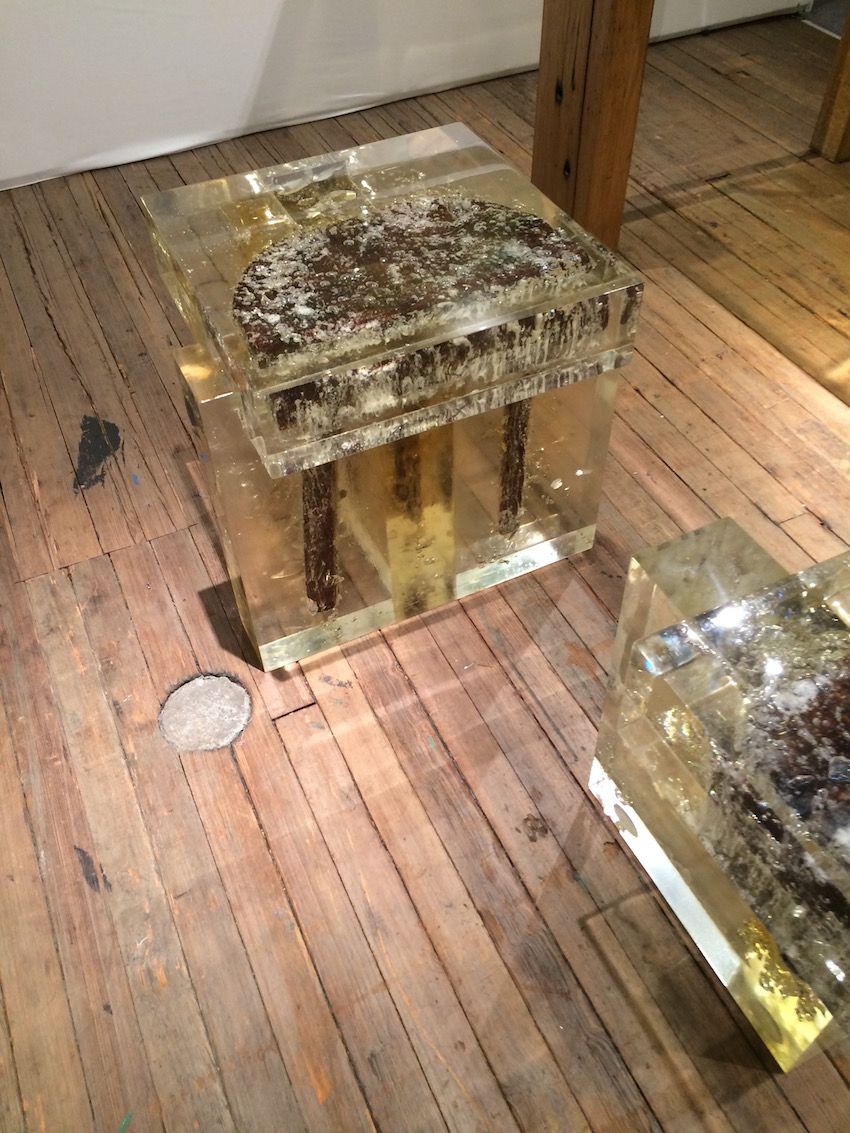 Inside the resin of the square bench, you can see one side of a round stool.