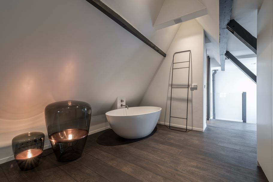 Attic bathroom decor with accent floor lighting and freestanding tub