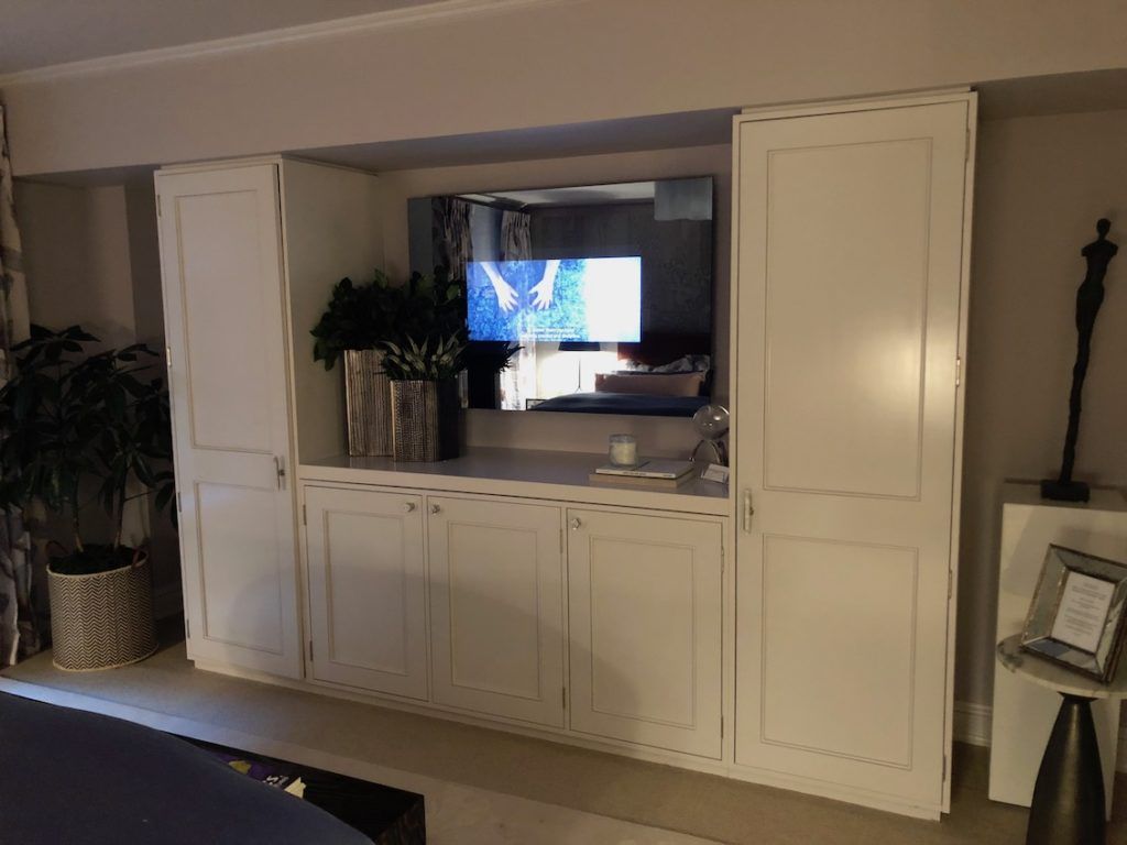 Across from the bed, the built-ins flank a television that is built into the mirror.