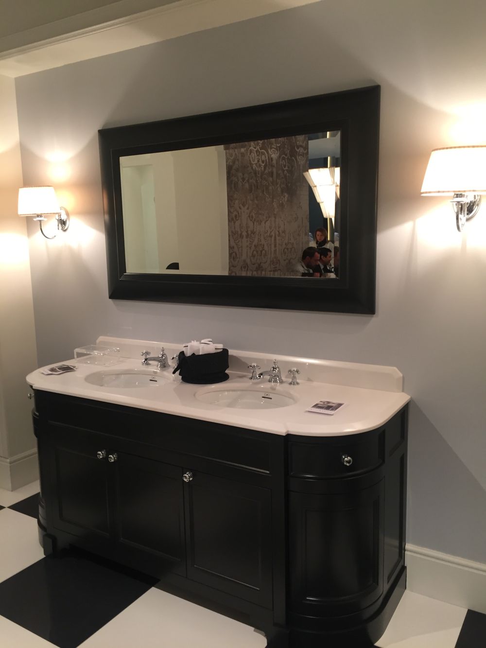 Black bathroom vanity with white top and wall lamps