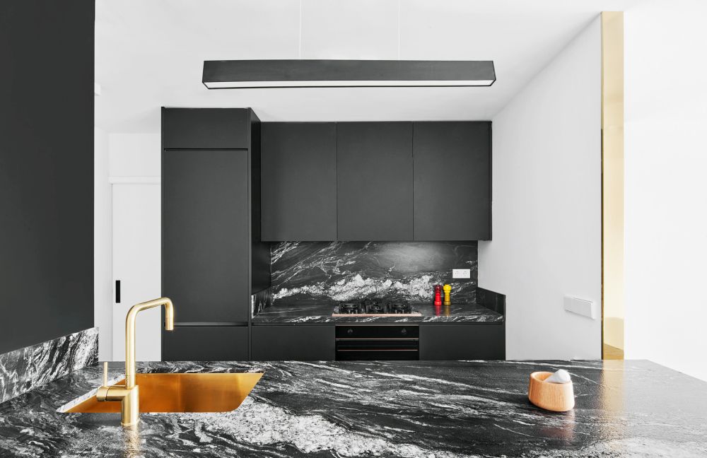 Black kitchen cabinets with marble counter top and backsplash featuring a copper sink