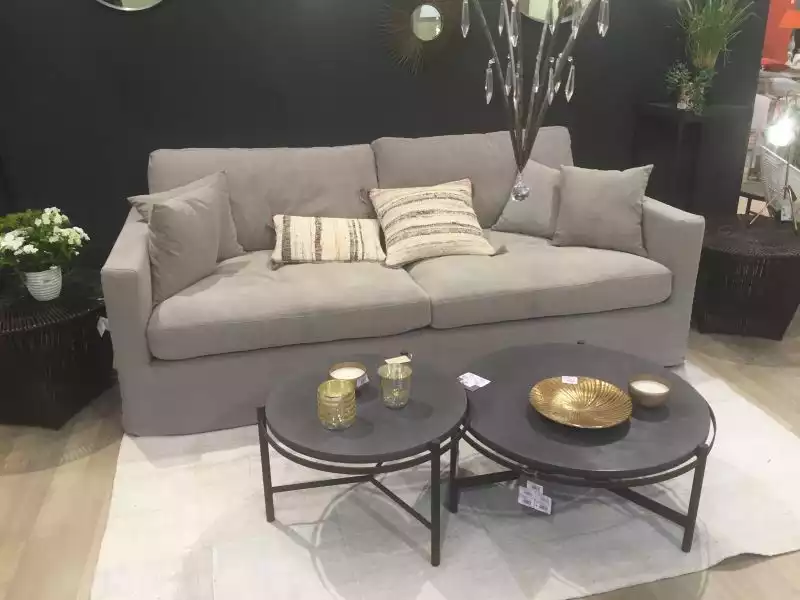 Black round coffee tables in front of a small grey couch