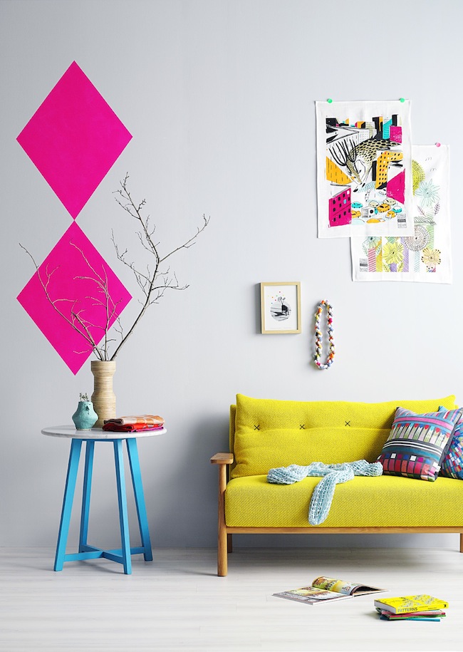 Bright yellow couch and a geometric pink wall decor