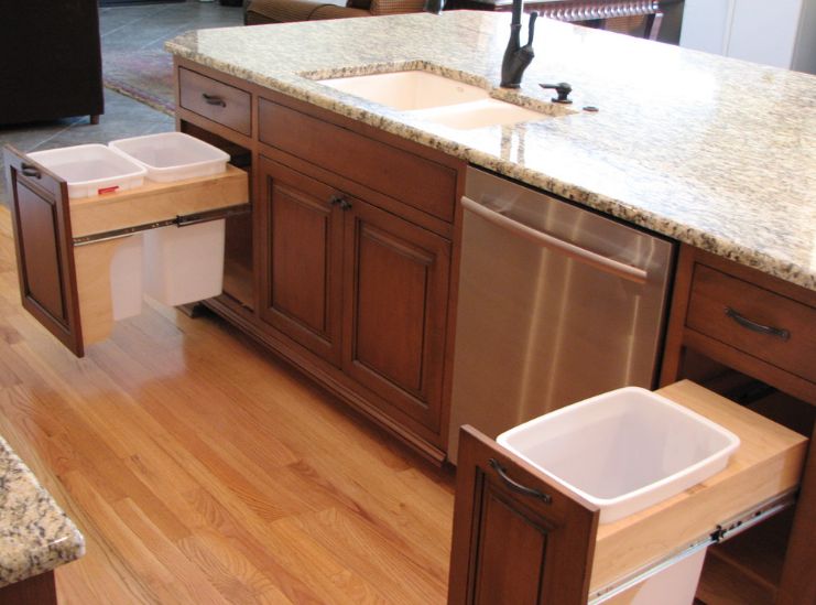 Brown kitchen cabinets with marble top and pull out trash systems