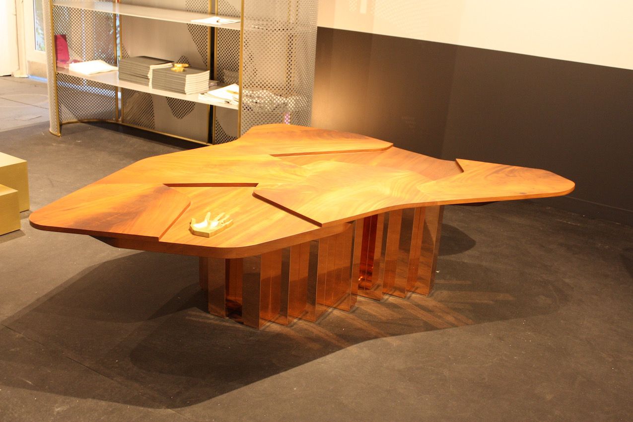 Gorgeous mahogany wood grain is enhanced by the uneven surface of this coffee table designed by Karen Chekerdjian. The shiny copper plated brass base provides a modern counterpoint to the warm wood. From the Carwan Gallery.