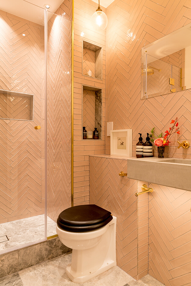 Chevron style tiles and pedestal walk in shower with glass panel