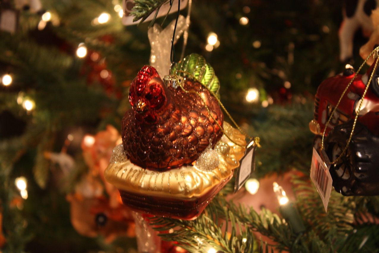 A glittery hen sits atop a basket in this whimsical little glass ornament.