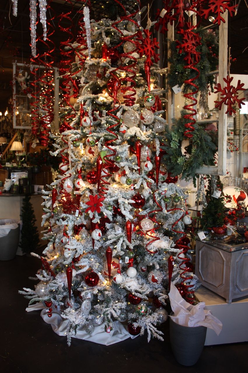 Red decorations really stand out on a tree that has been flocked white.