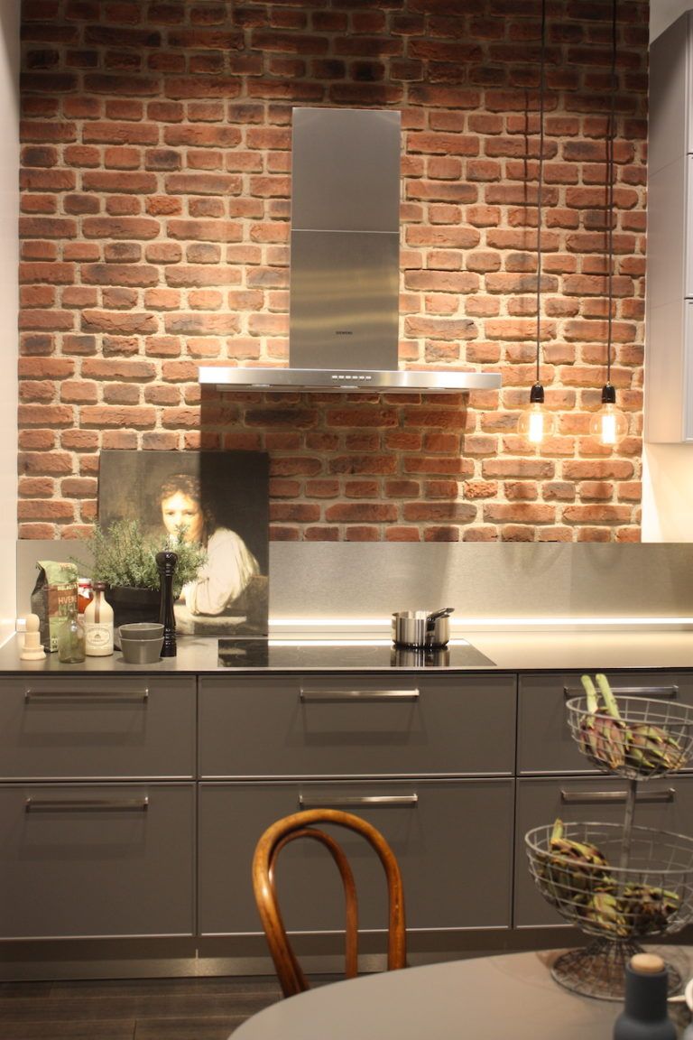 Exposed brick with stainless steel countertop and a small backsplash