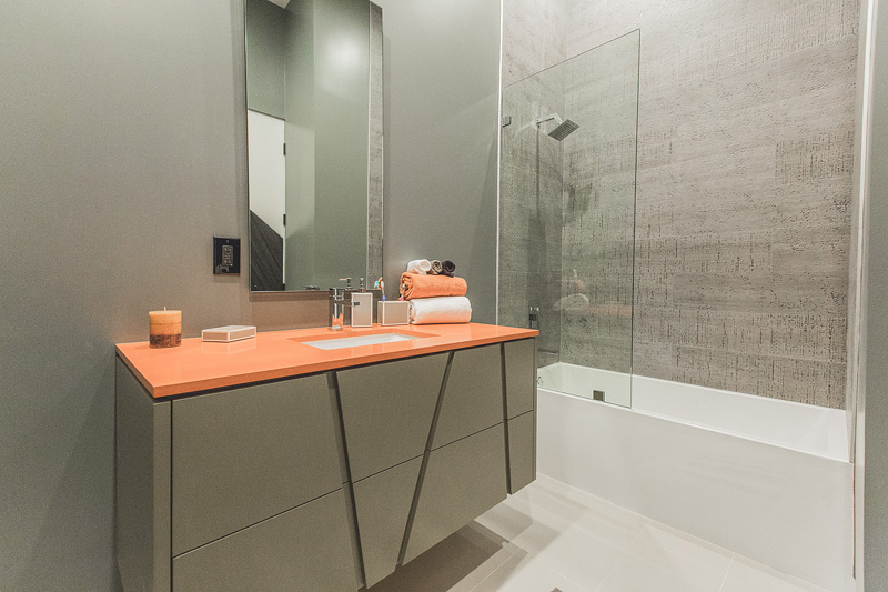 Gray walls and pop of orange through vanity countertop