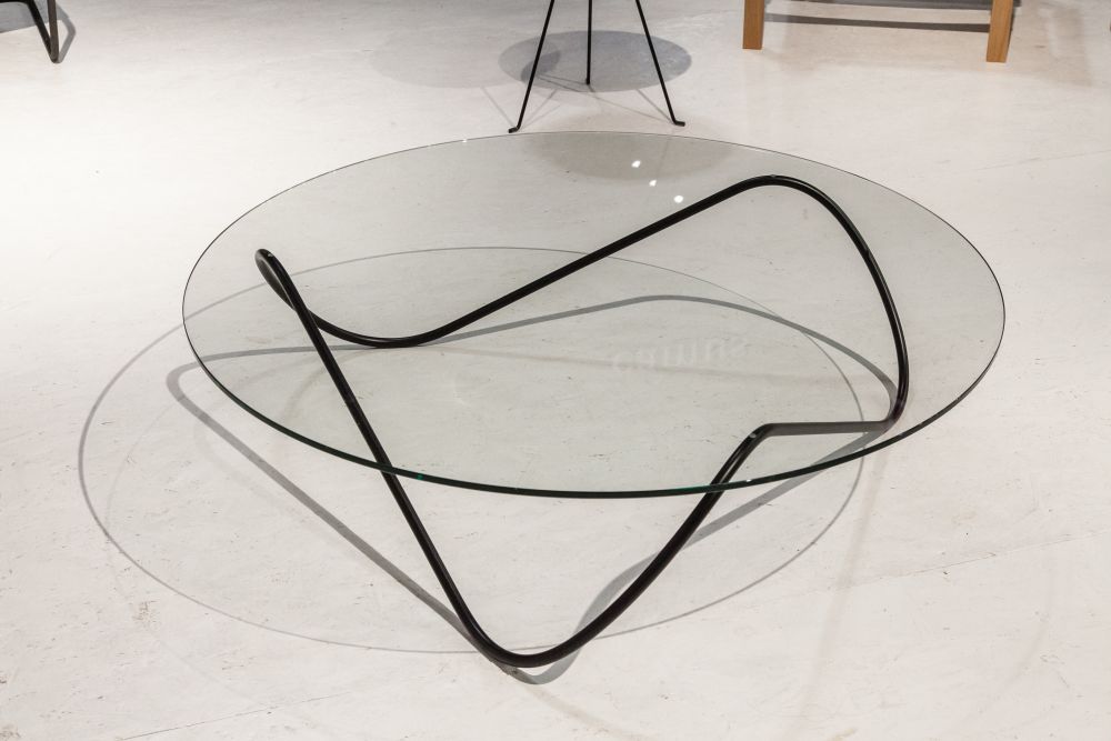 The sleek, fluid base of this table touches the glass top and the floor in three points, being perfectly balanced