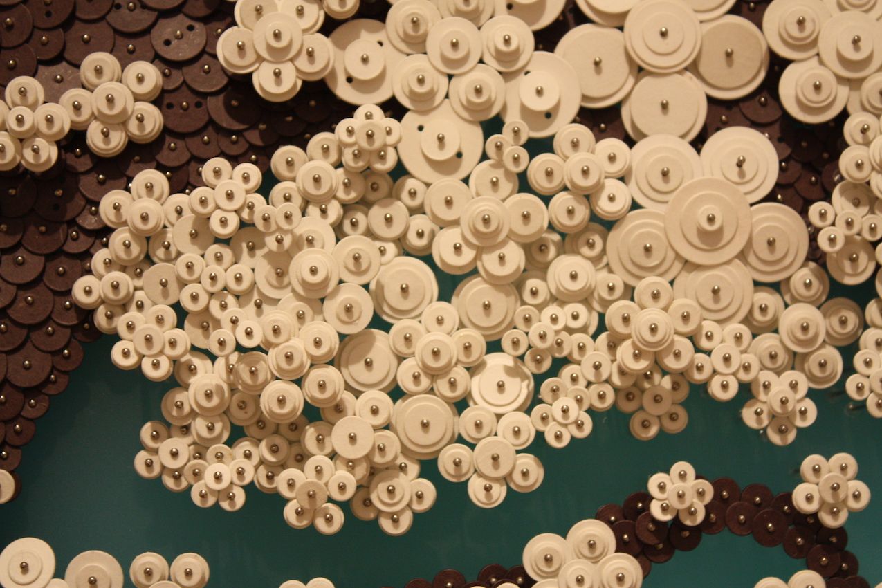 Paper buttons of many sizes are used to create texture and dimension.