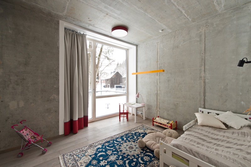 The concrete walls and ceiling are softened by textile rugs, curtains and other highlights