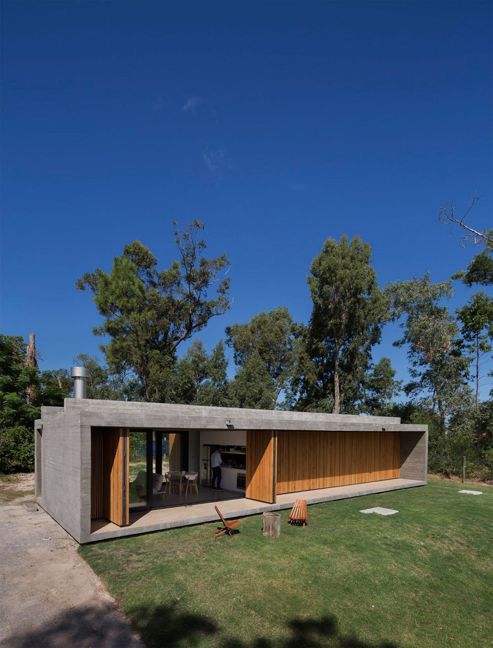 The house is long and rectangular and has a single level and a concrete shell