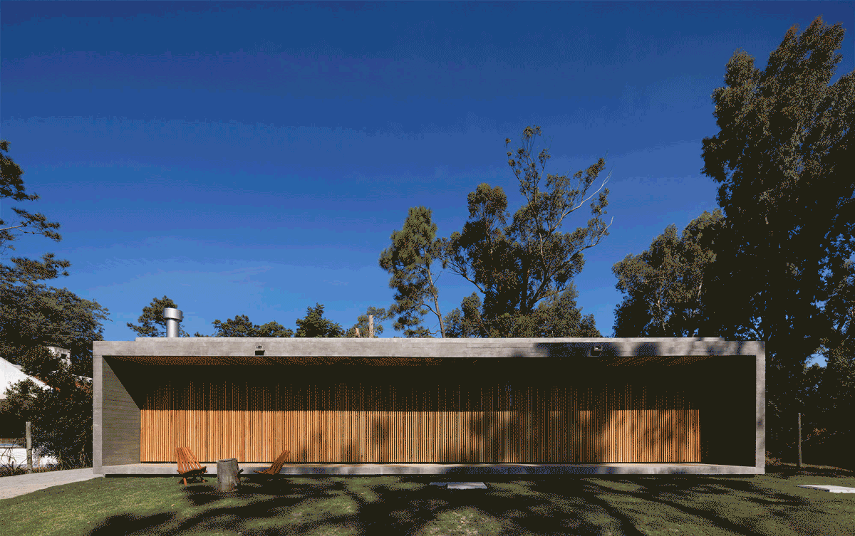 The back of the house has a glazed facade covered with wood slat panels that open up in sections to let the light and the view in