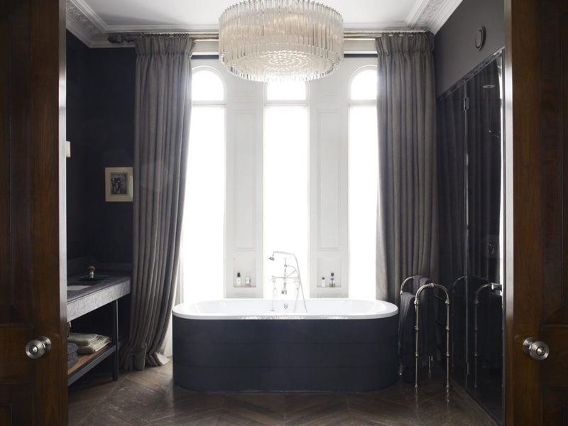 Masculine bathroom design with chandelier and large curtains