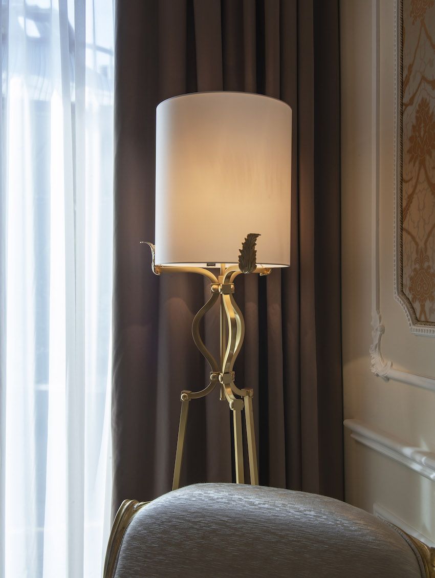 A floor lamp has an elegant brass base with leaf details.